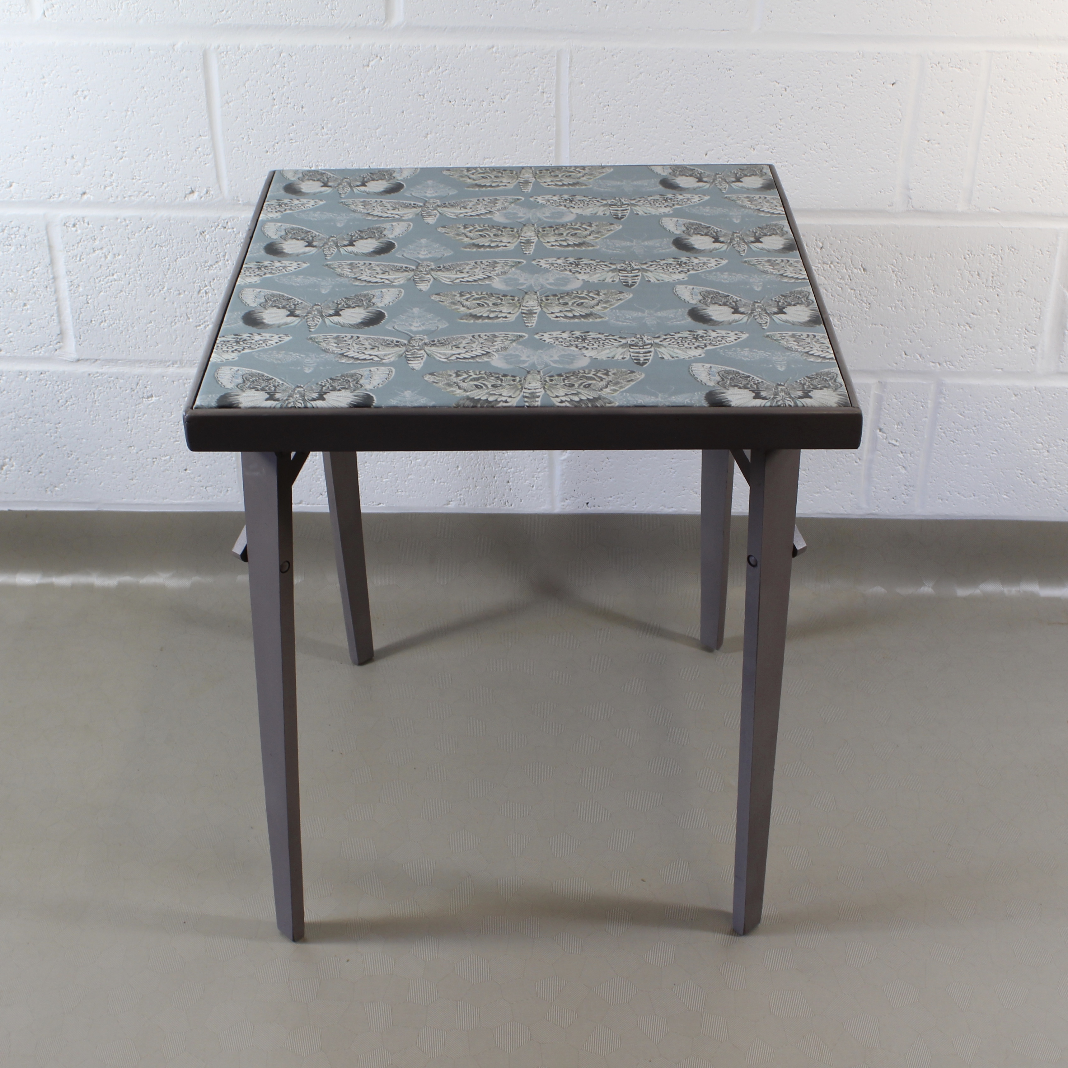An up-cycled folding occasional table covered in Voyage Nocturnal in seathistle.